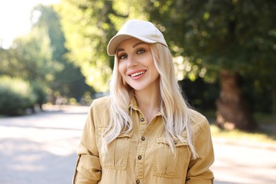 Photo of Portrait of smiling woman in baseball cap outdoors