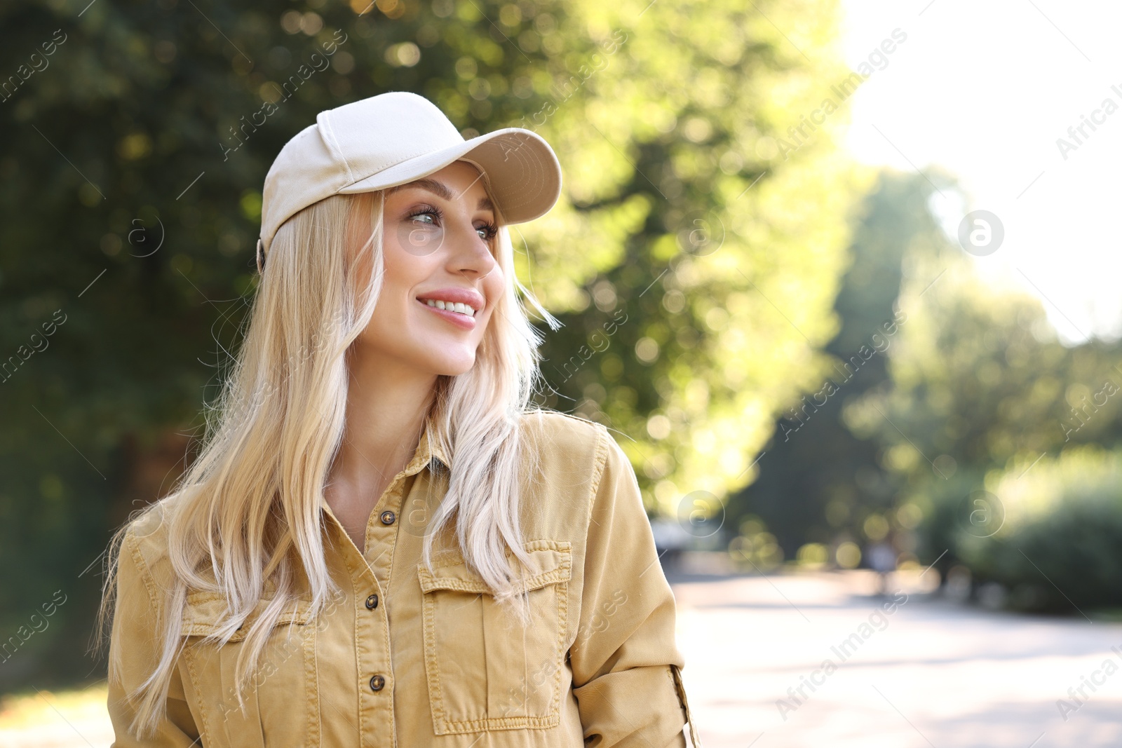 Photo of Portrait of smiling woman in baseball cap outdoors, space for text