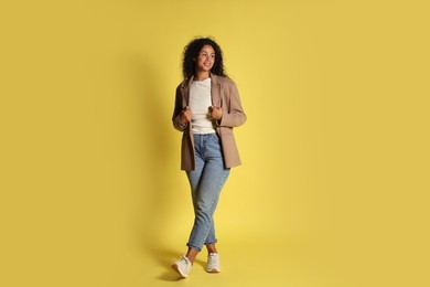 Beautiful woman in stylish jacket on yellow background