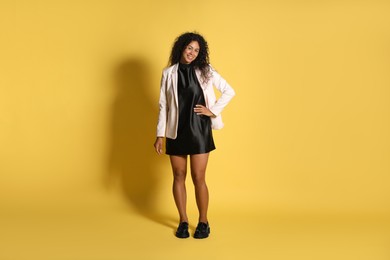 Photo of Beautiful woman in stylish jacket on yellow background