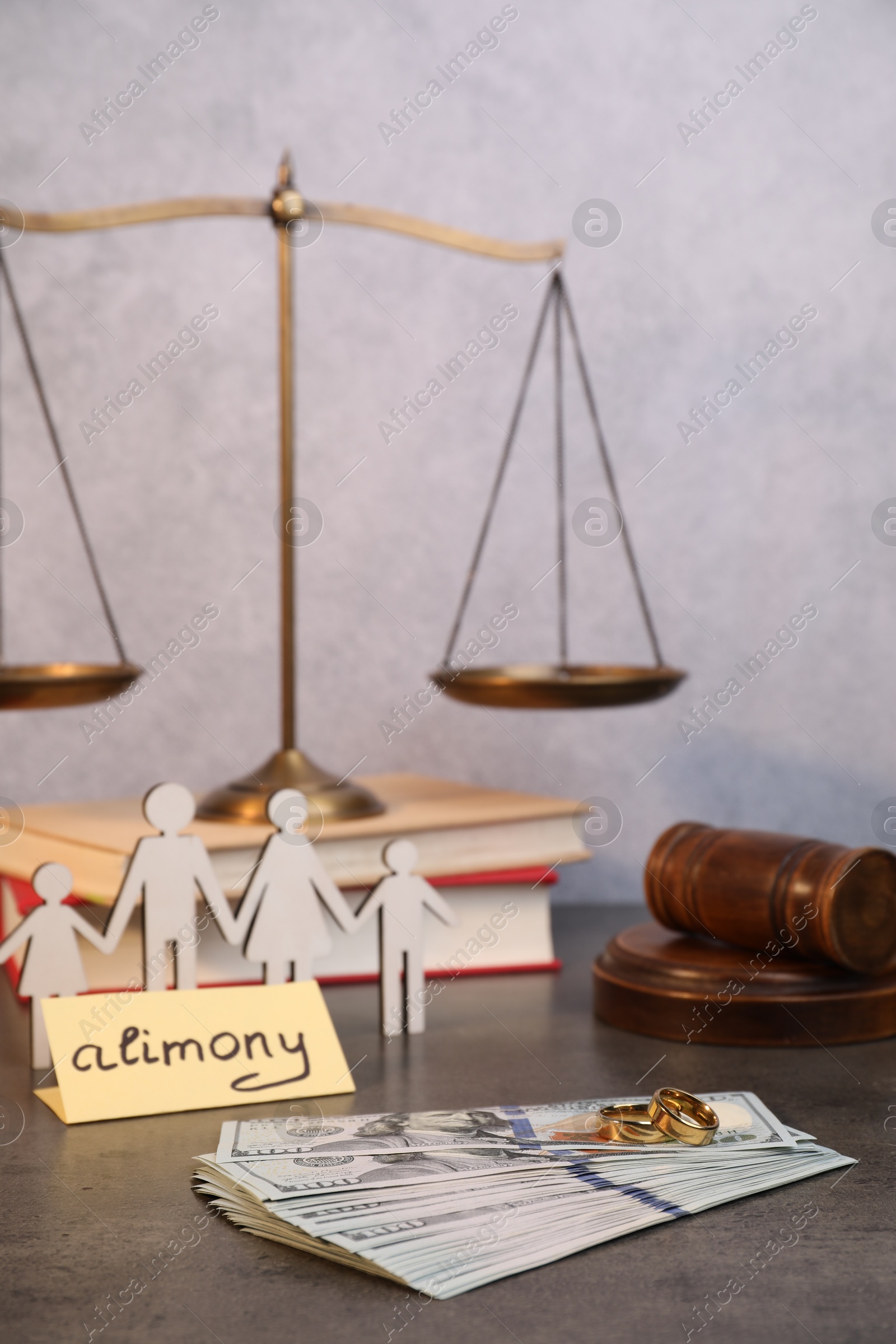 Photo of Card with word Alimony, dollar banknotes, figures of family, wooden gavel and scales on grey table