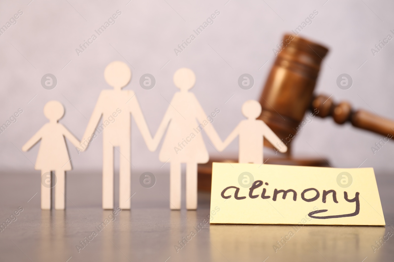 Photo of Card with word Alimony and figures of family on grey table, closeup