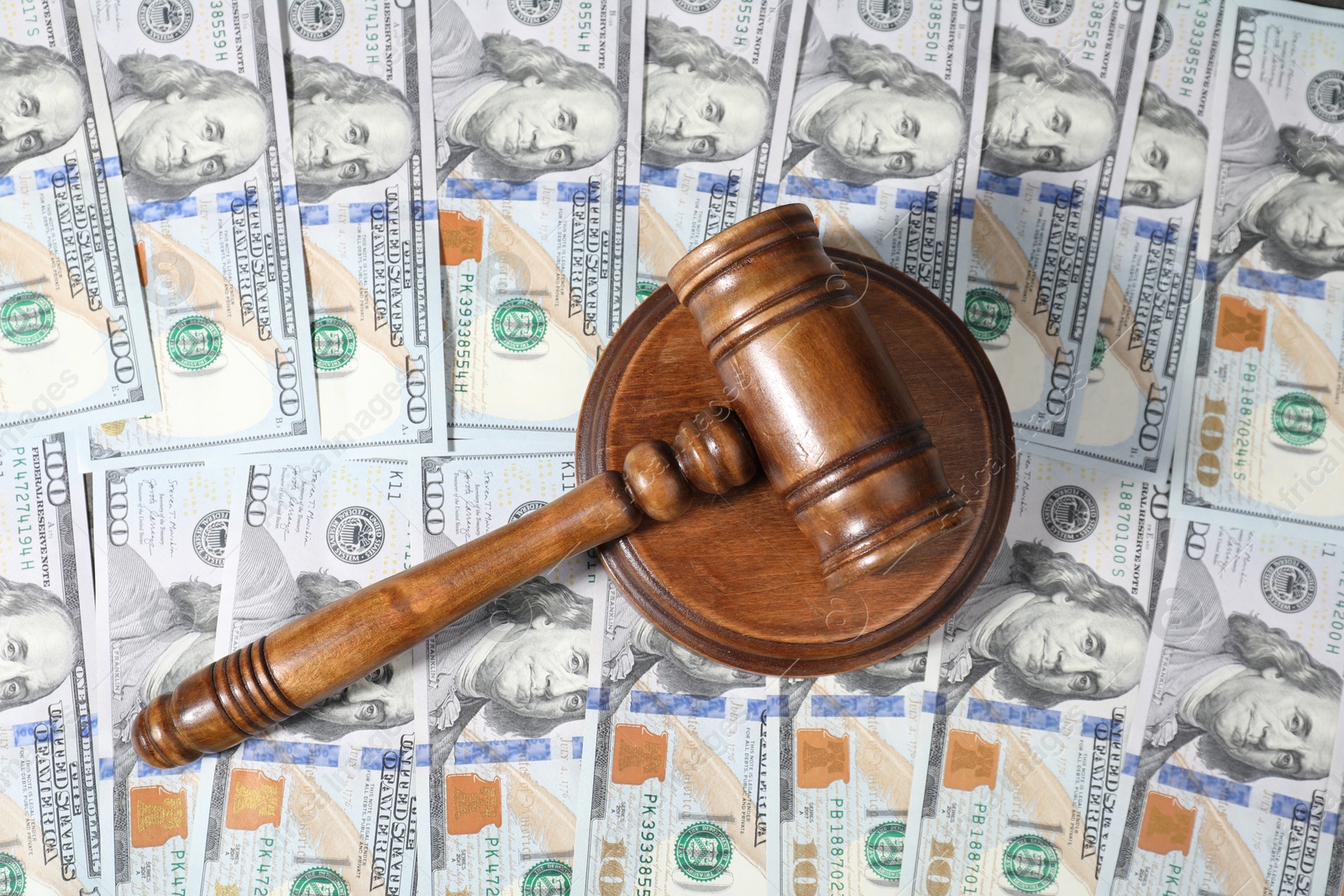 Photo of Alimony. Wooden gavel on dollar banknotes, top view