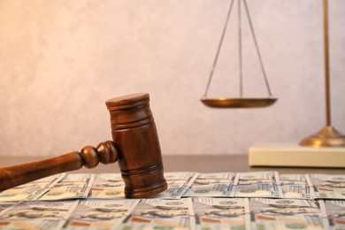 Photo of Alimony. Wooden gavel and dollar banknotes on table