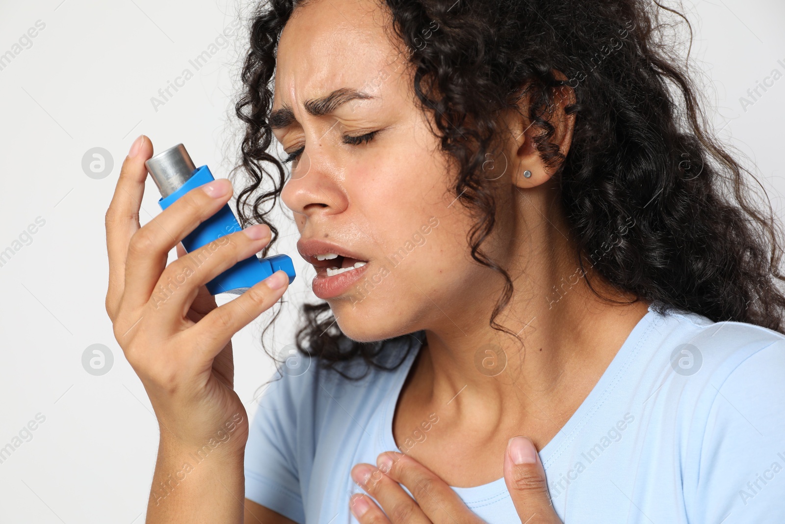 Photo of Young woman using asthma inhaler on white background, closeup