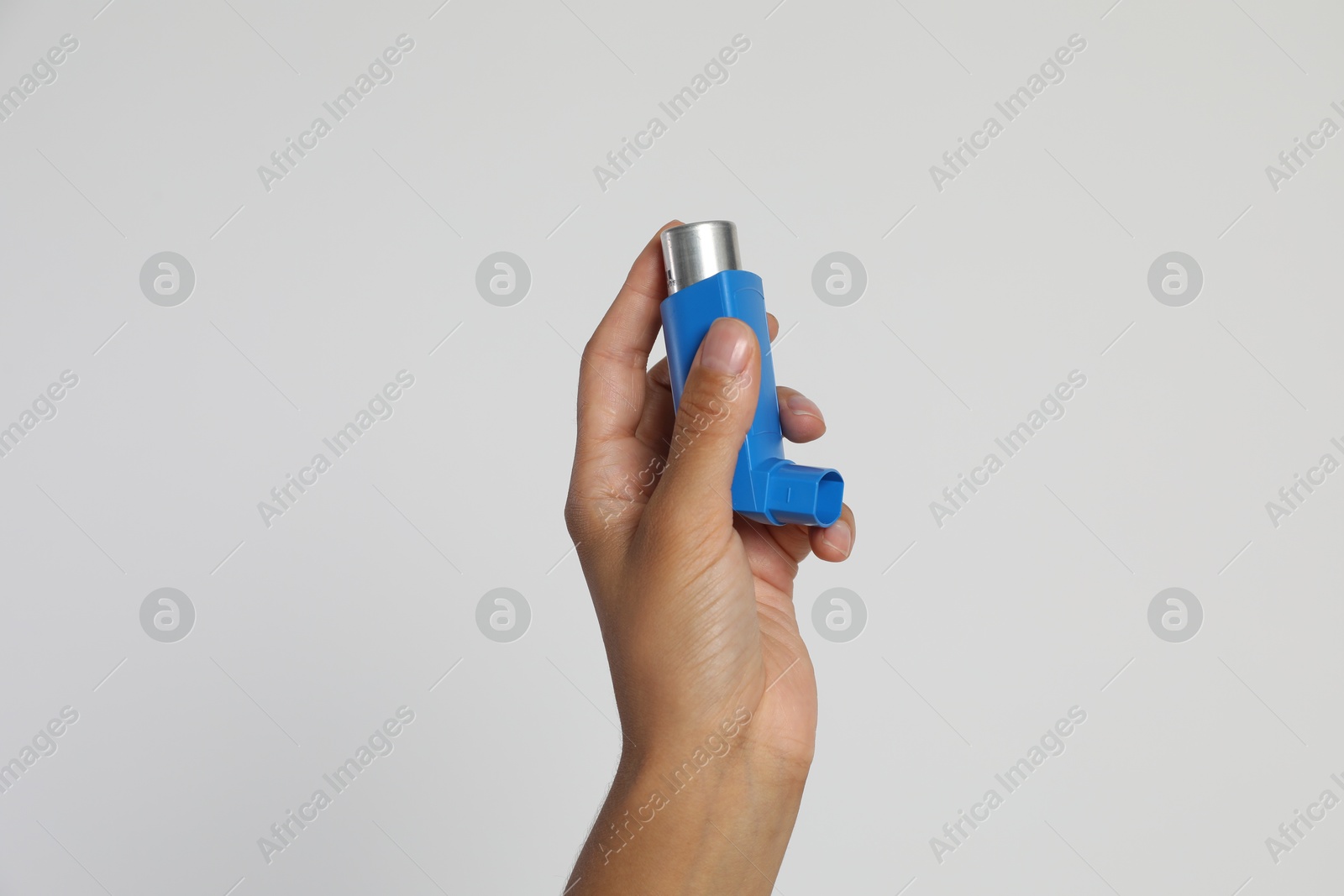 Photo of Woman holding asthma inhaler on light grey background, closeup