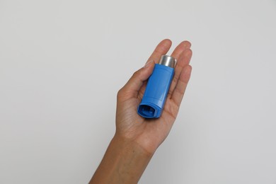 Photo of Woman holding asthma inhaler on light grey background, closeup