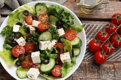 Photo of Delicious salad with feta cheese on wooden table, flat lay