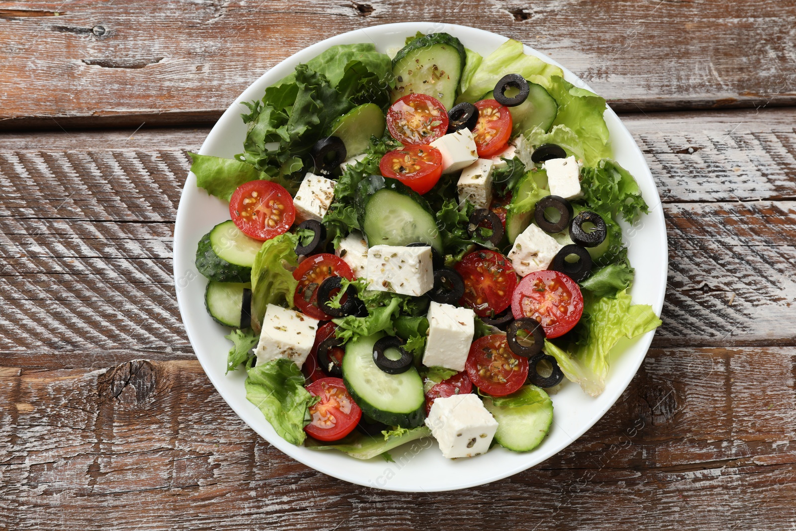 Photo of Delicious salad with feta cheese on wooden table, top view