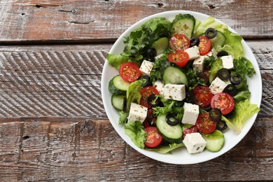 Photo of Delicious salad with feta cheese on wooden table, top view. Space for text