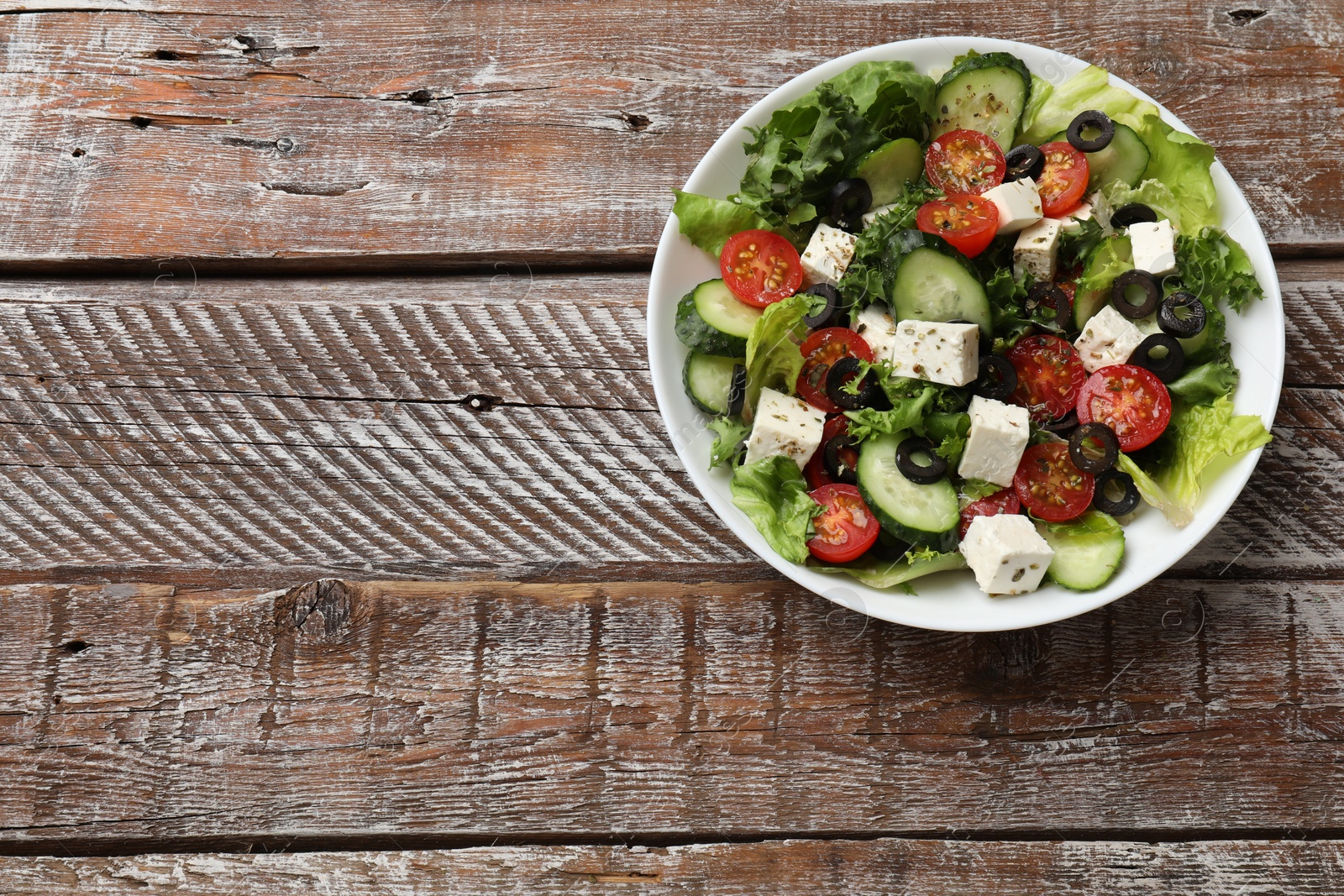 Photo of Delicious salad with feta cheese on wooden table, top view. Space for text