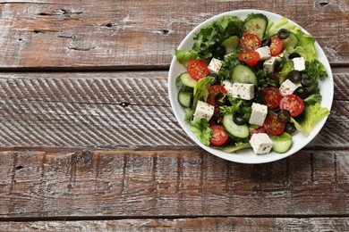 Photo of Delicious salad with feta cheese on wooden table, top view. Space for text