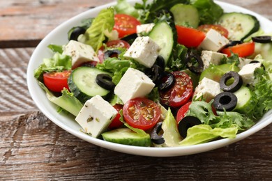 Photo of Delicious salad with feta cheese on wooden table, closeup