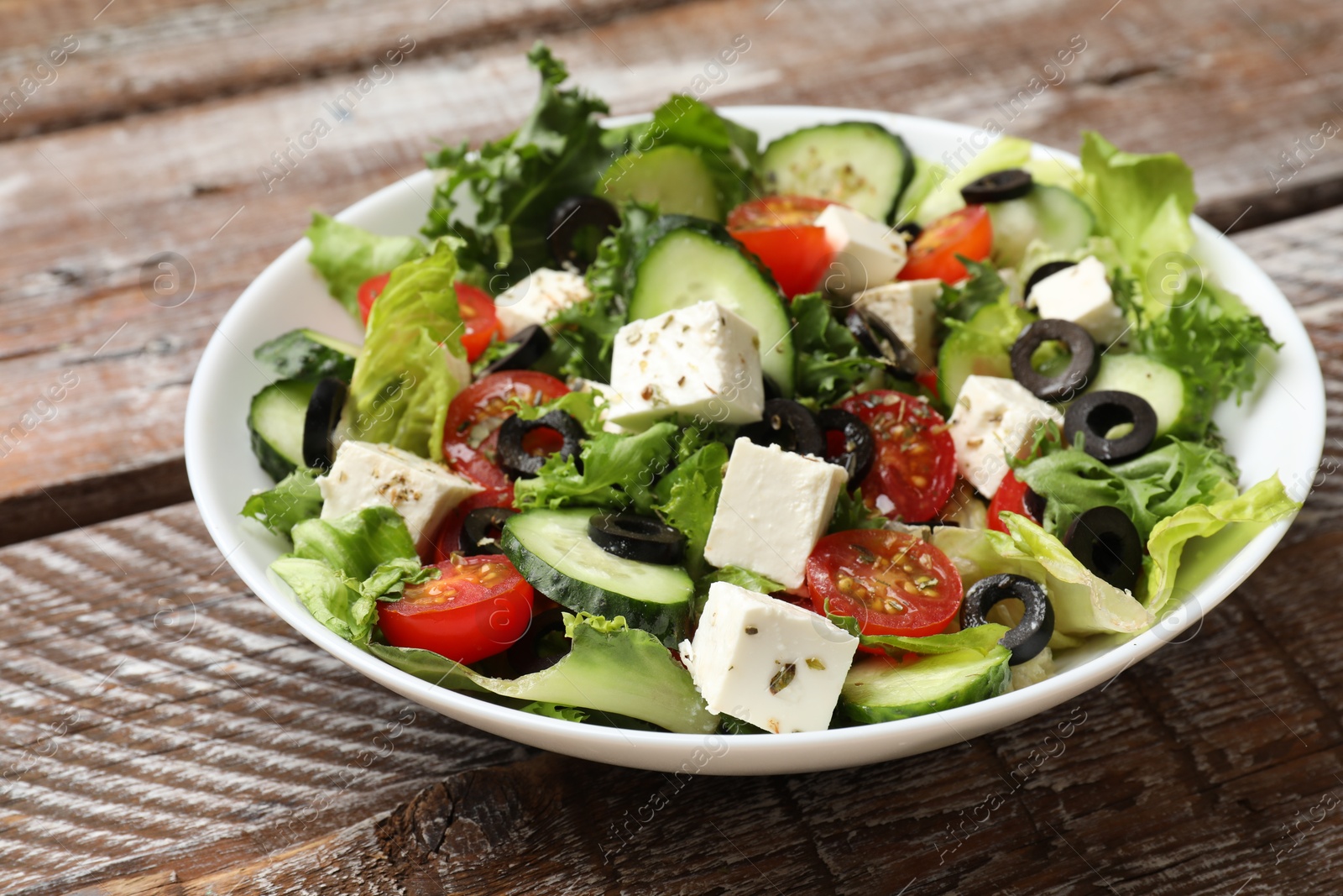 Photo of Delicious salad with feta cheese on wooden table, closeup