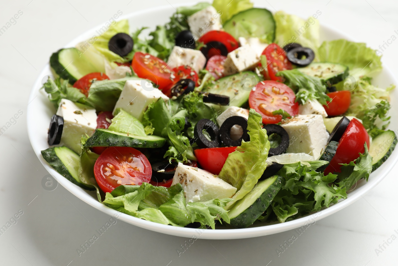 Photo of Delicious salad with feta cheese on white marble table, closeup