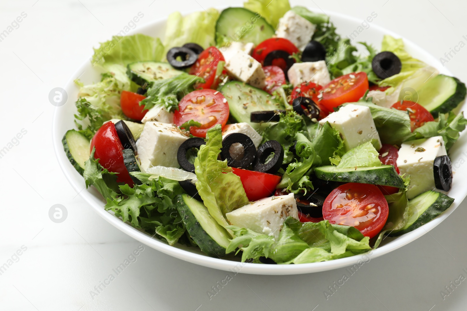 Photo of Delicious salad with feta cheese on white marble table, closeup