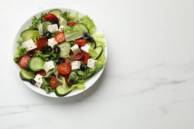 Delicious salad with feta cheese on white marble table, top view. Space for text