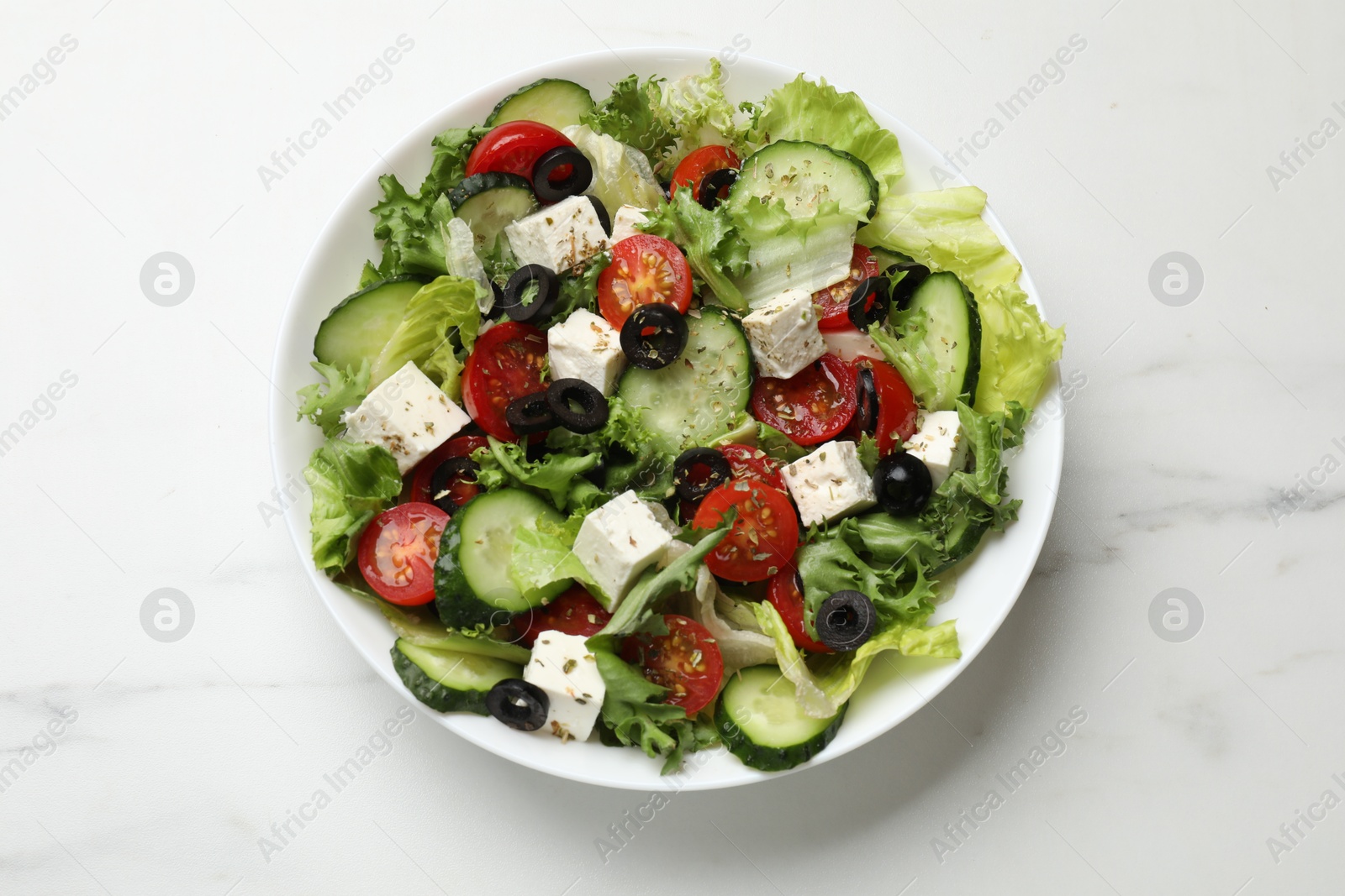 Photo of Delicious salad with feta cheese on white marble table, top view