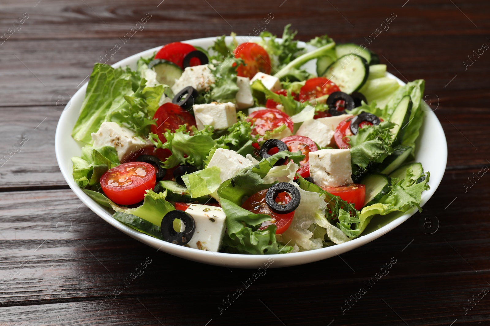 Photo of Delicious salad with feta cheese on wooden table, closeup