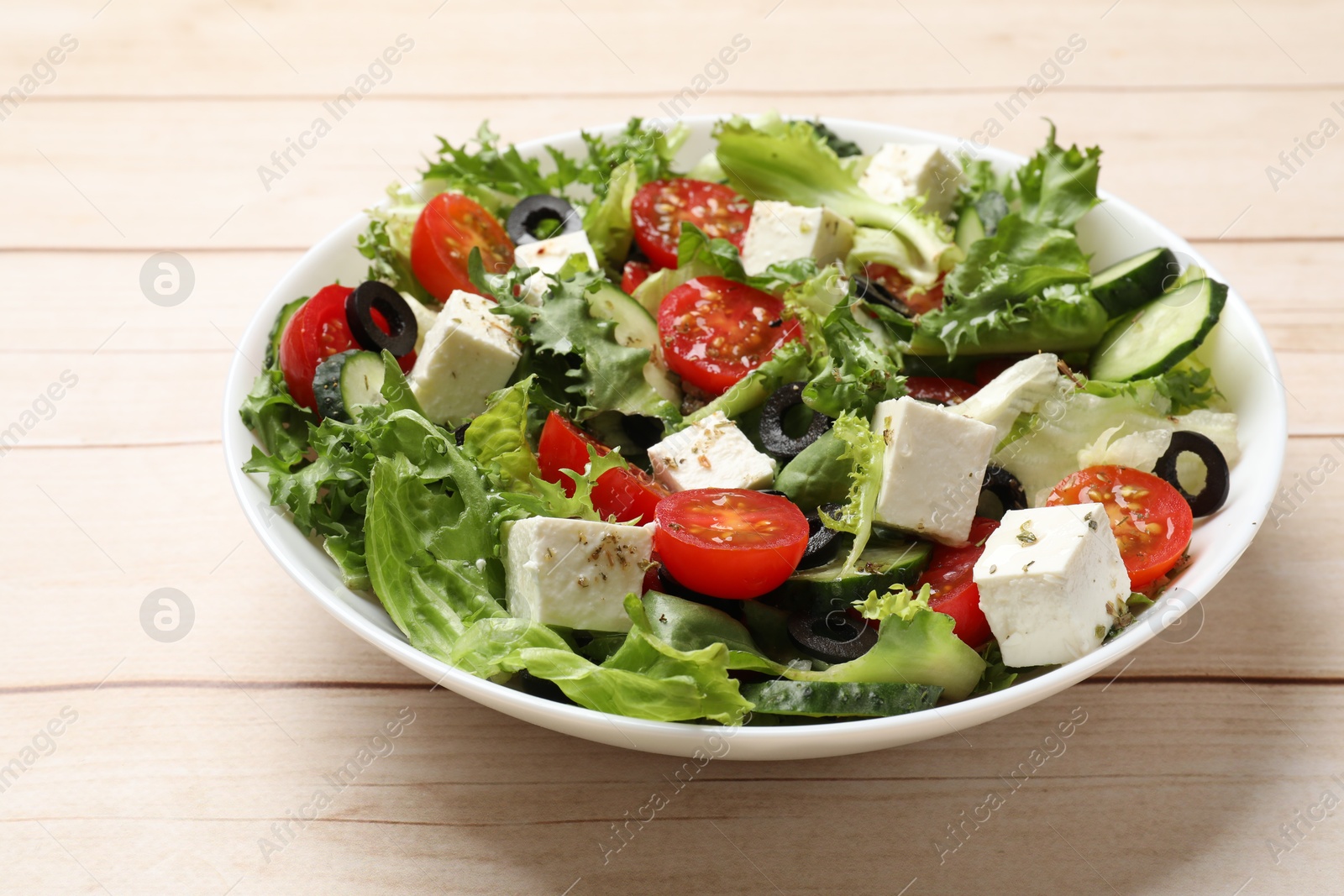 Photo of Delicious salad with feta cheese on white wooden table, closeup