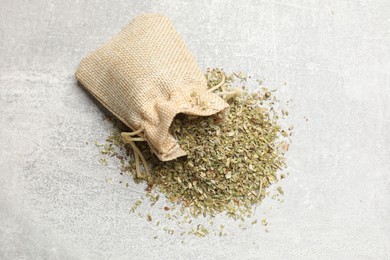 Sack with dried oregano on grey table, top view