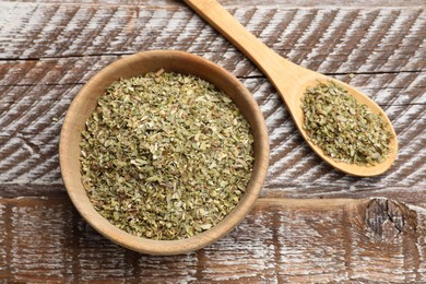 Photo of Dried oregano in bowl and spoon on wooden table, top view