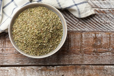 Photo of Dried oregano in bowl on wooden table, top view. Space for text