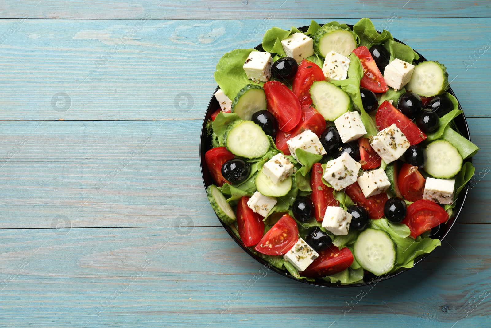 Photo of Delicious salad with feta cheese on light blue wooden table, top view. Space for text