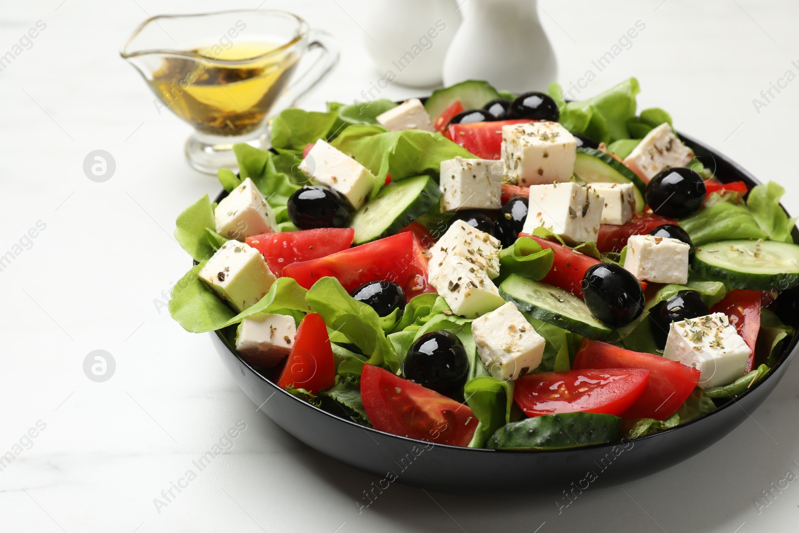 Photo of Delicious salad with feta cheese served on white marble table, closeup