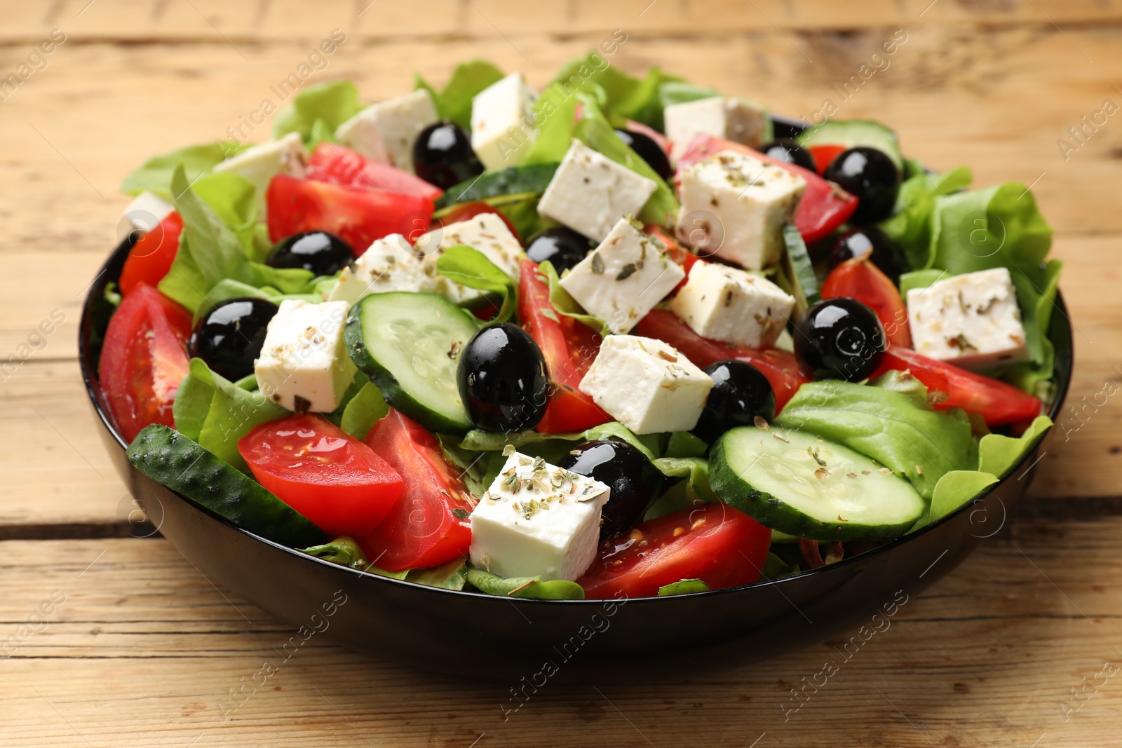 Photo of Delicious salad with feta cheese on wooden table, closeup