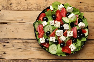 Photo of Delicious salad with feta cheese on wooden table, top view. Space for text