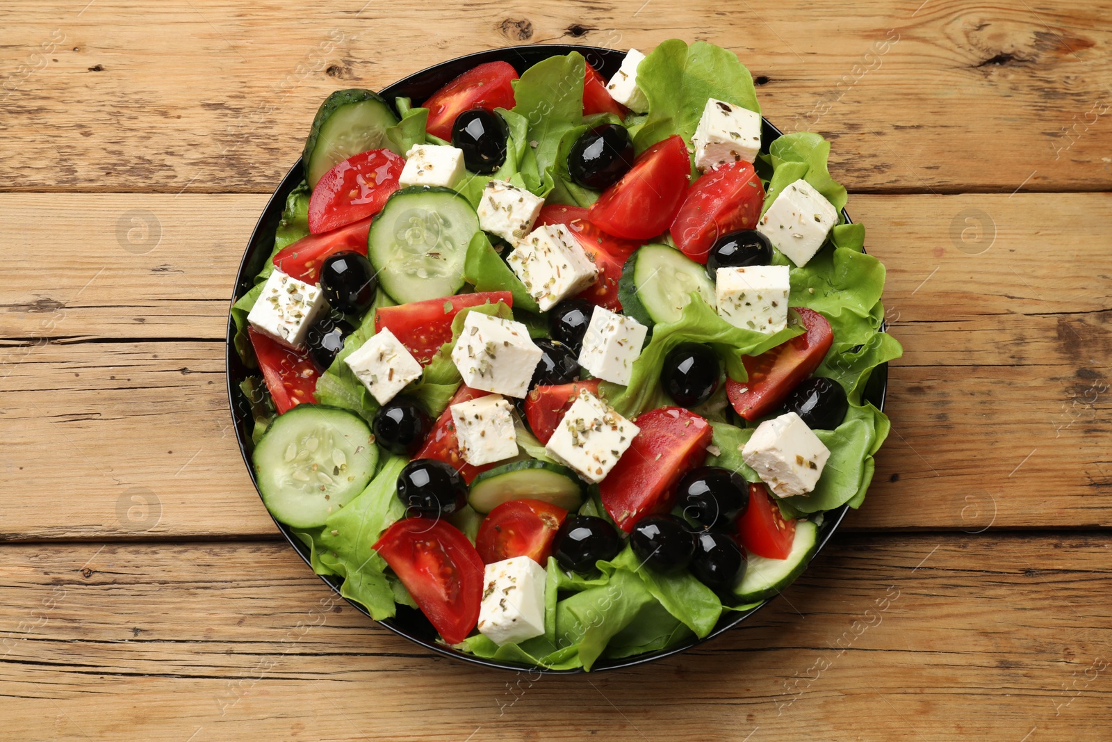 Photo of Delicious salad with feta cheese on wooden table, top view