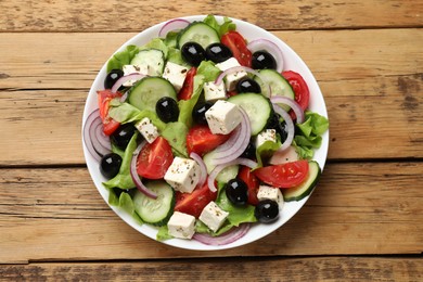 Photo of Delicious salad with feta cheese on wooden table, top view