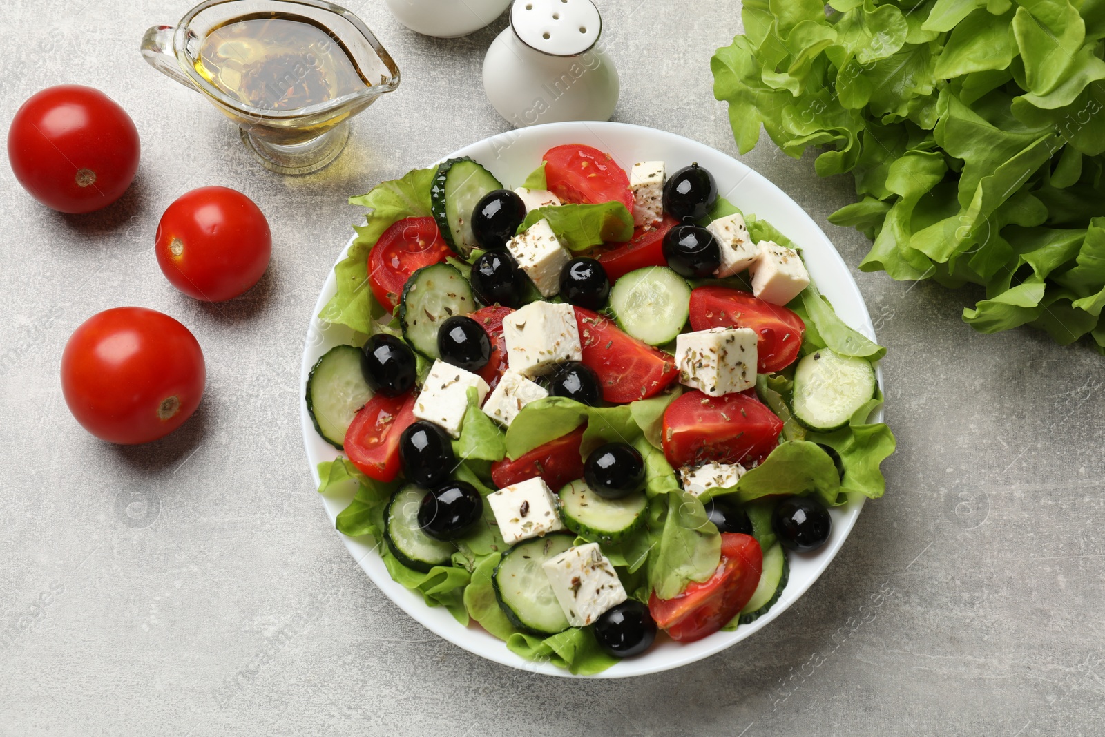 Photo of Delicious salad with feta cheese and ingredients on grey table, flat lay