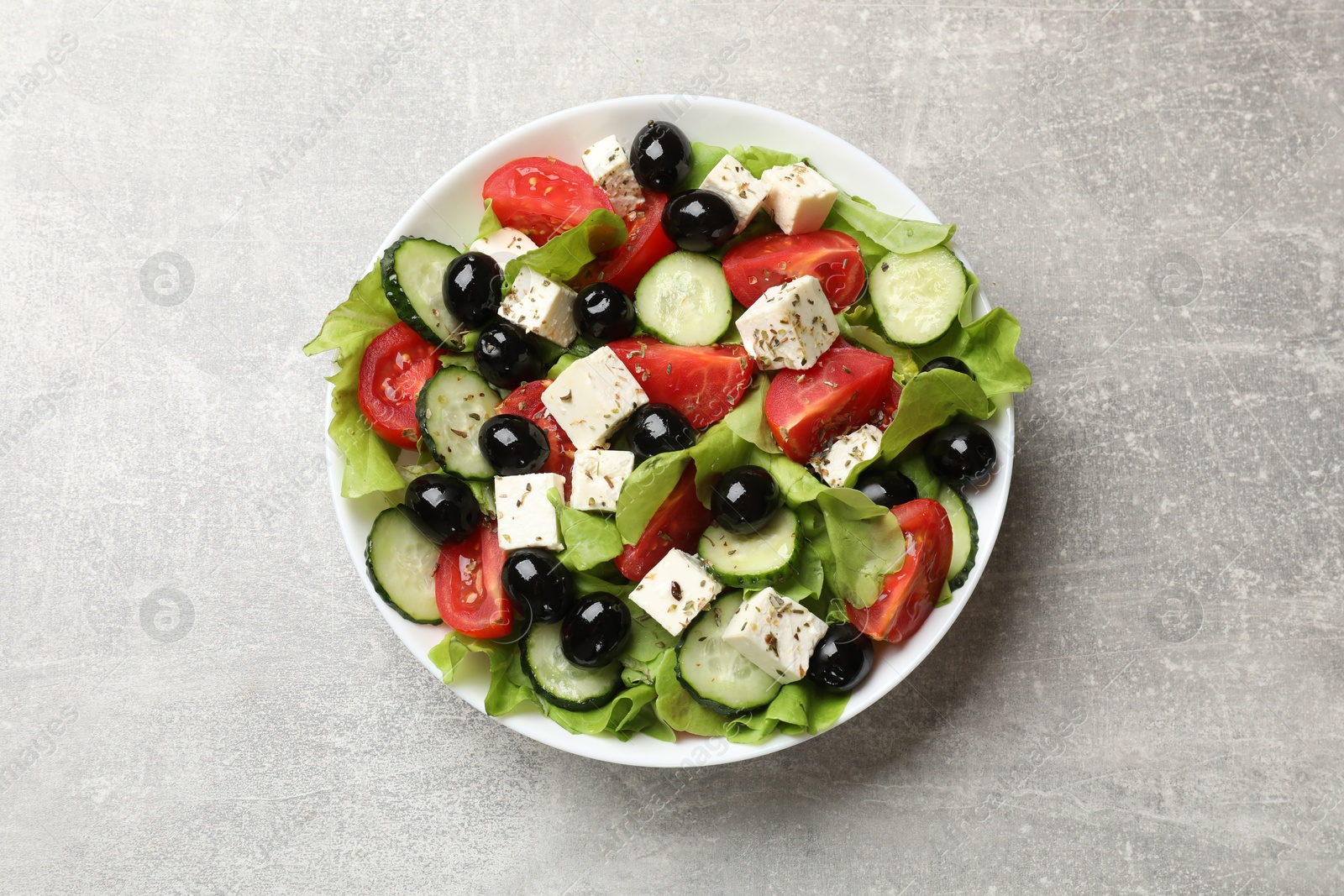 Photo of Delicious salad with feta cheese on grey table, top view