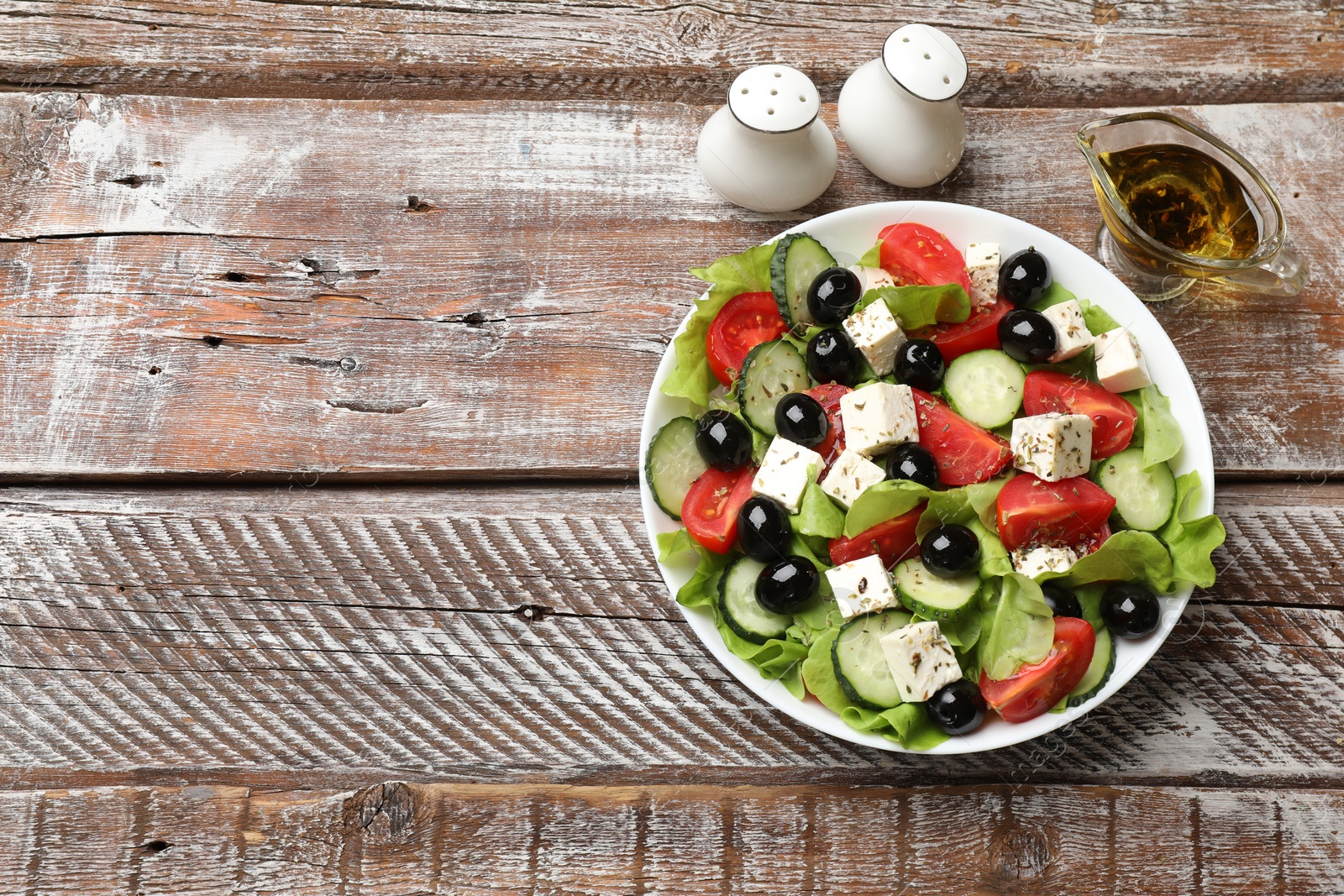 Photo of Delicious salad with feta cheese served on wooden table, flat lay. Space for text