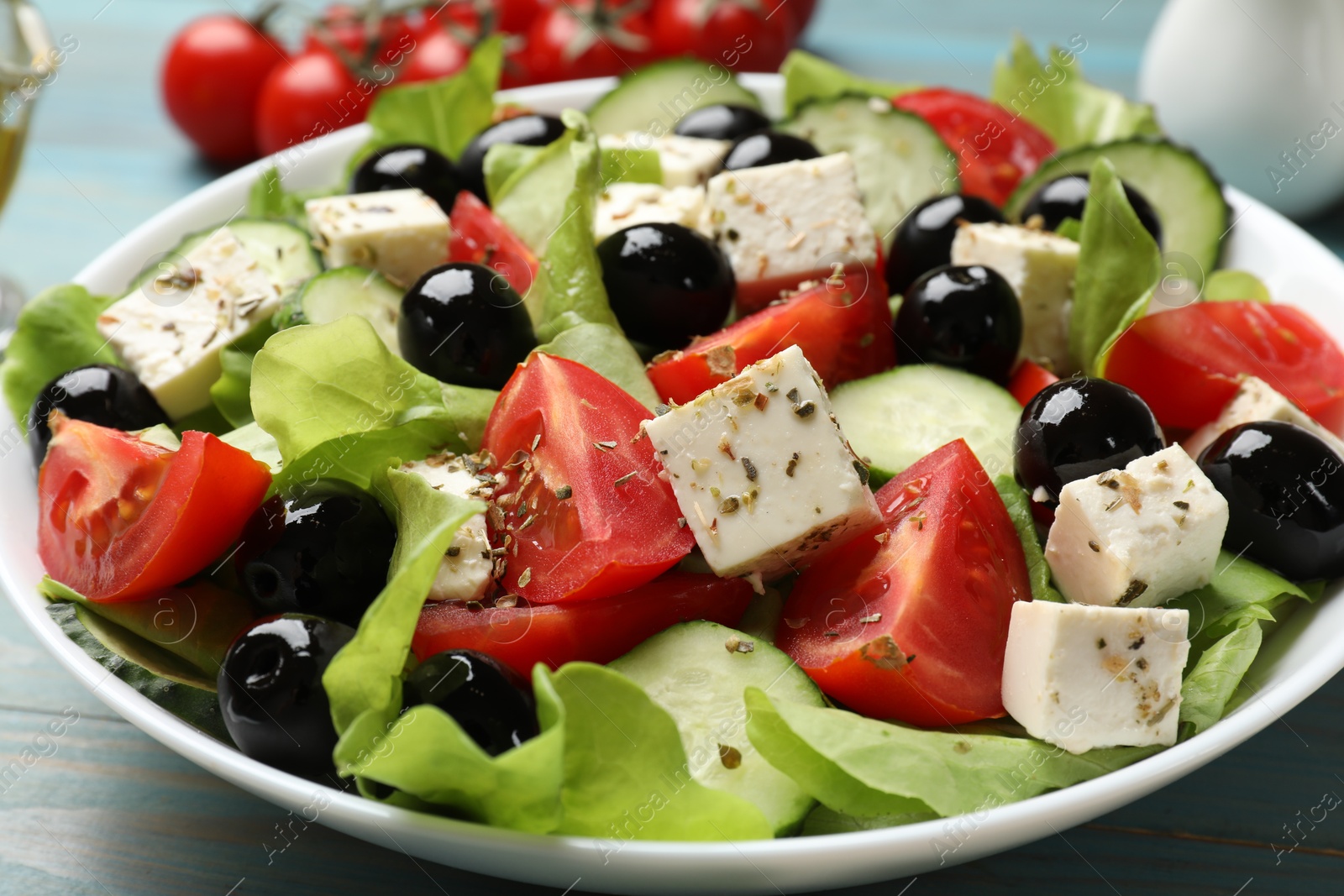 Photo of Delicious salad with feta cheese on light blue wooden table, closeup