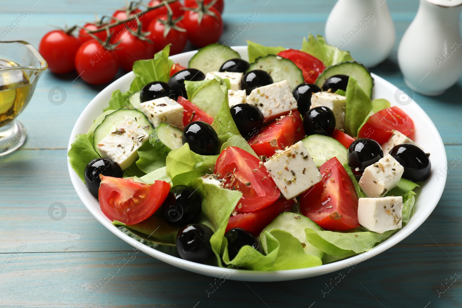 Photo of Delicious salad with feta cheese on light blue wooden table, closeup