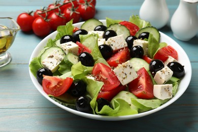 Photo of Delicious salad with feta cheese on light blue wooden table, closeup