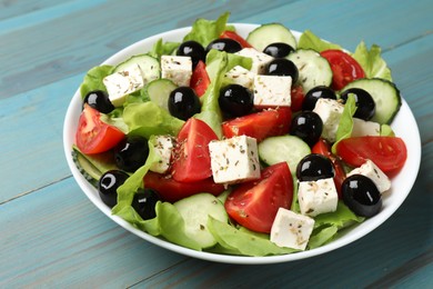 Photo of Delicious salad with feta cheese on light blue wooden table, closeup