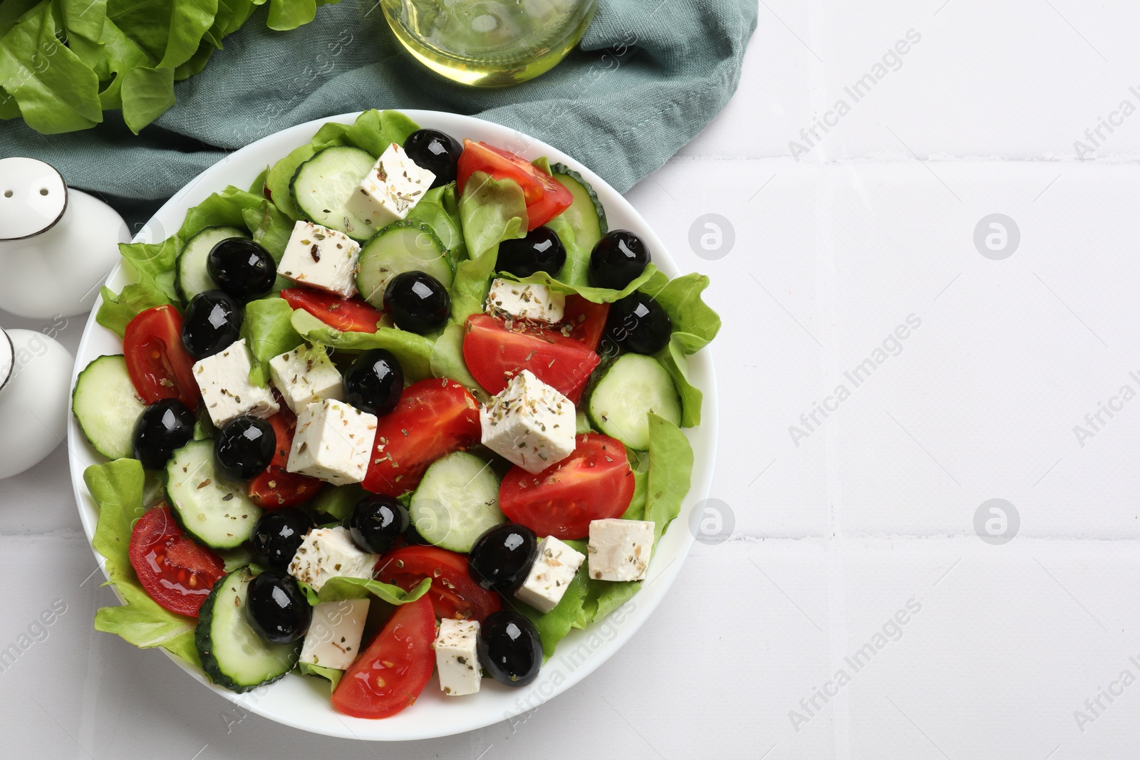 Photo of Delicious salad with feta cheese served on white tiled table, flat lay. Space for text