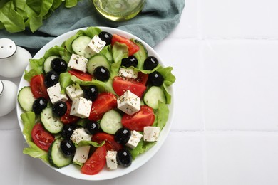 Photo of Delicious salad with feta cheese served on white tiled table, flat lay. Space for text