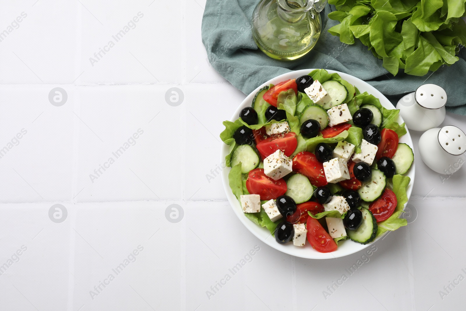 Photo of Delicious salad with feta cheese served on white tiled table, flat lay. Space for text