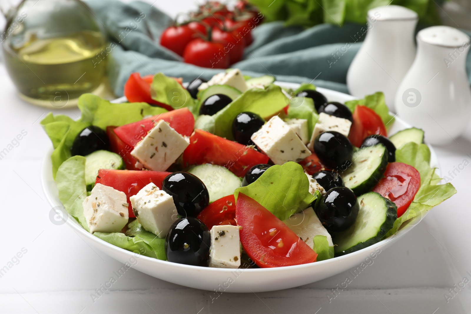 Photo of Delicious salad with feta cheese on white tiled table, closeup