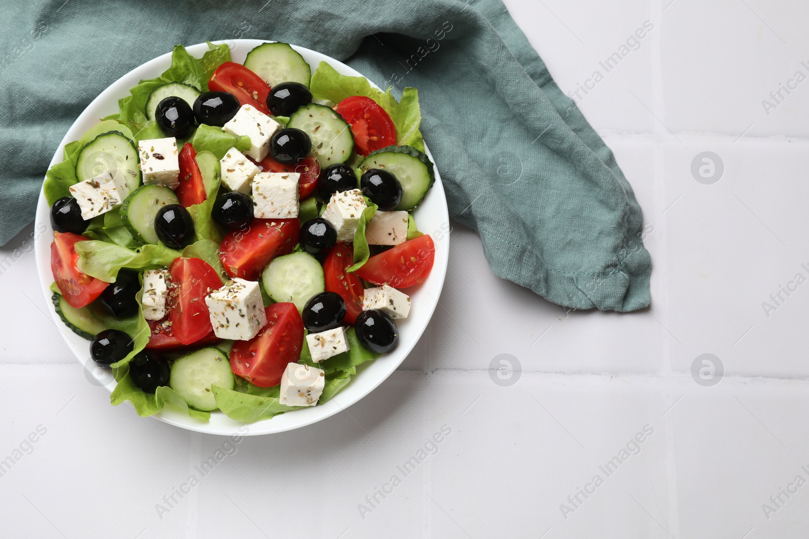 Photo of Delicious salad with feta cheese on white tiled table, top view. Space for text