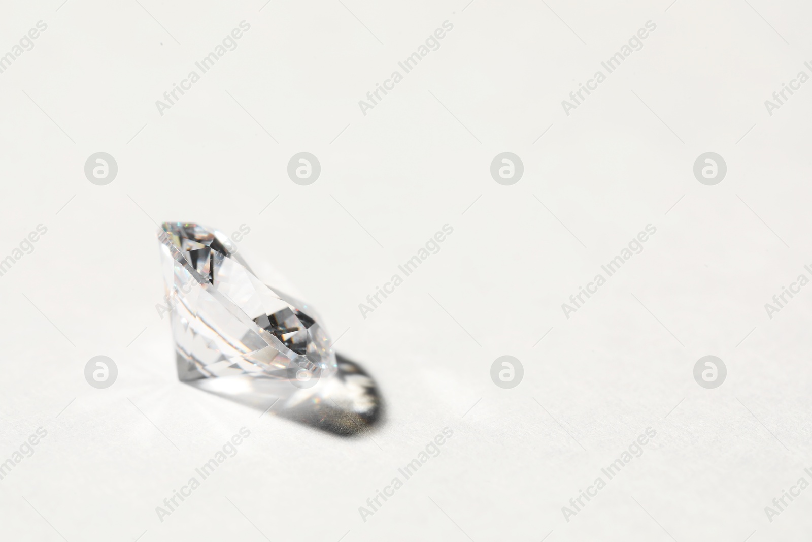 Photo of Beautiful shiny diamond on white background, closeup. Space for text