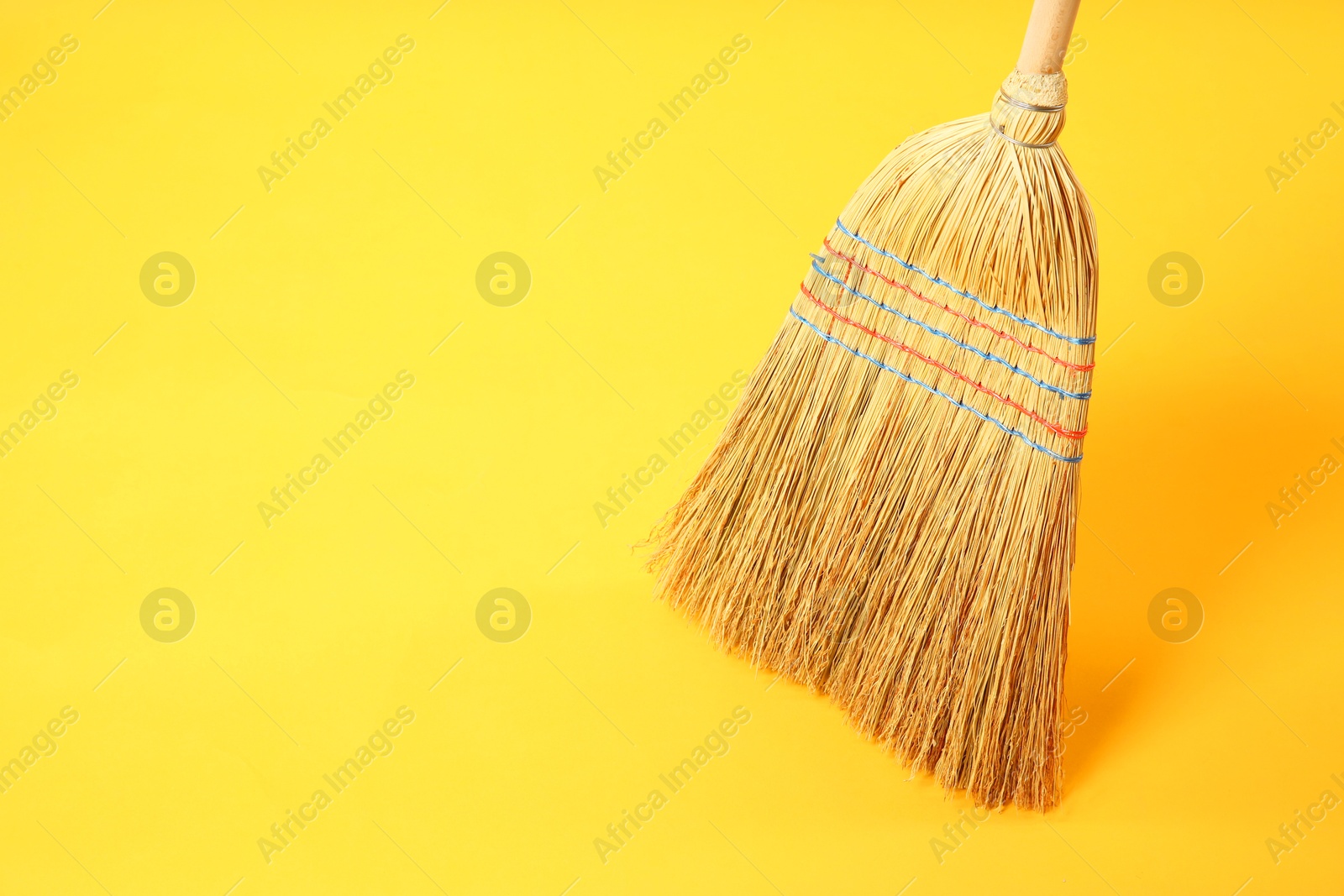 Photo of One corn straw broom on yellow background, space for text