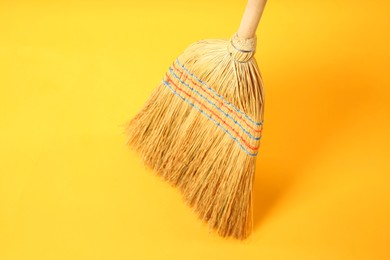 Photo of One corn straw broom on yellow background