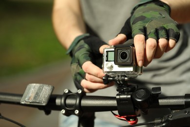 Man with modern action camera on bicycle outdoors, closeup