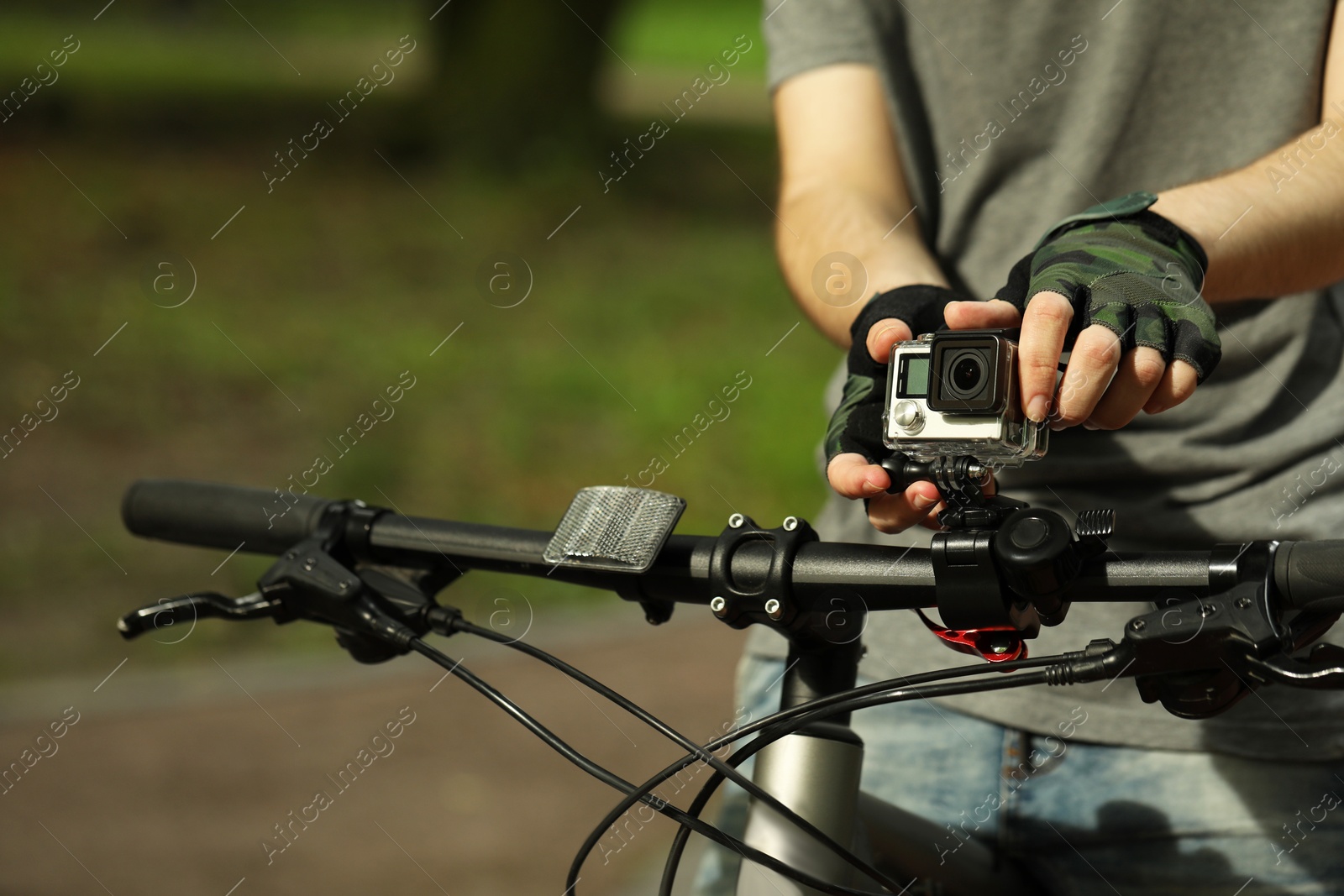 Photo of Man with modern action camera on bicycle outdoors, closeup